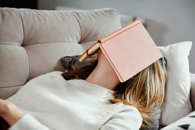 A woman falls asleep with a book covering her face