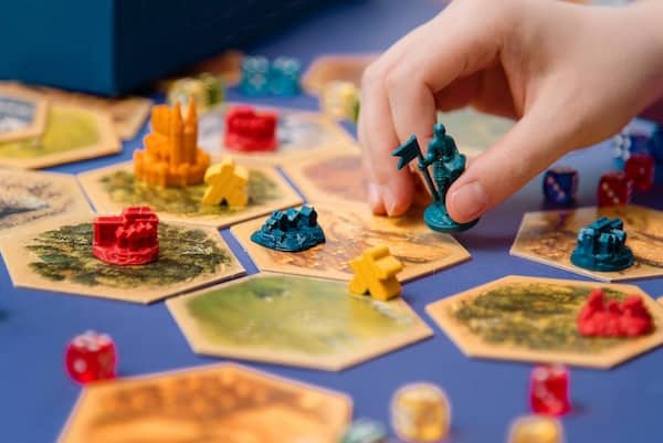 A hand moves a board game piece across a tile.