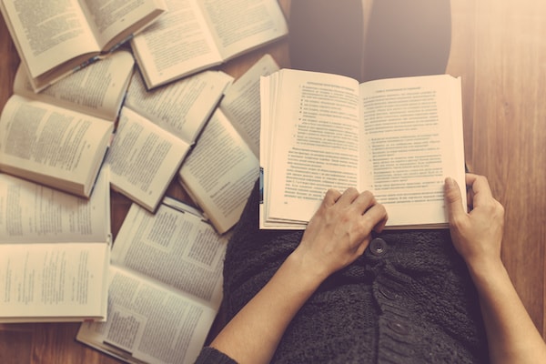 A person flicking through open books on the floor