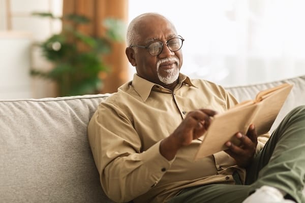 A person sits on a sofa and reads a book.