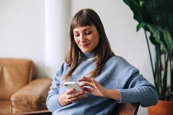 A woman types on her phone and smiles.