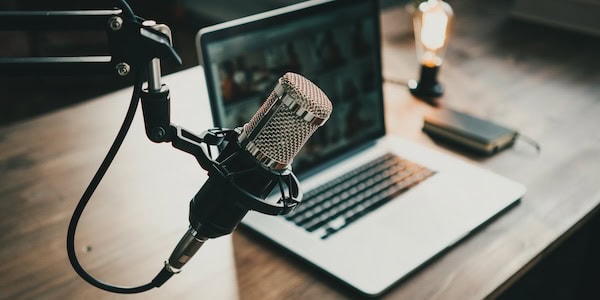 A podcast set up, including a microphone and laptop on a desk.