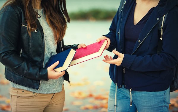 Friends exchanging books.