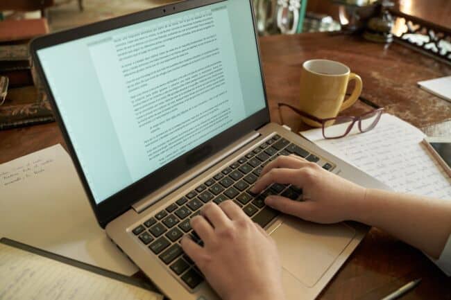 An author typing up their book into a word document on a laptop