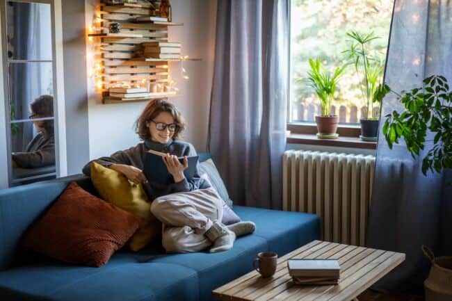 A person ready a book on a cosy sofa with fairy lights.