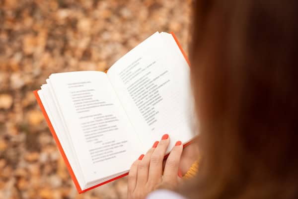 A person holding an open book of poetry.
