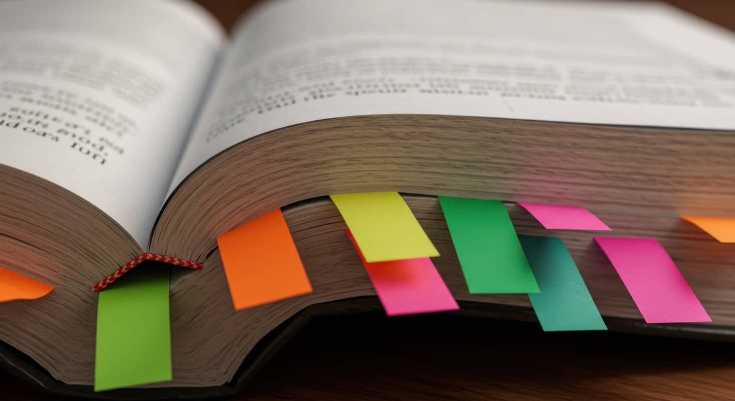 Close-up view of an open book with several colorful sticky notes inserted between its pages.