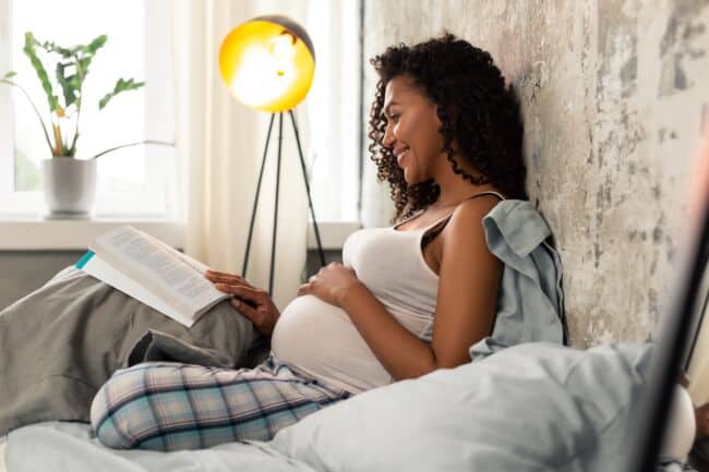 Pregnant women reading a book on her bed