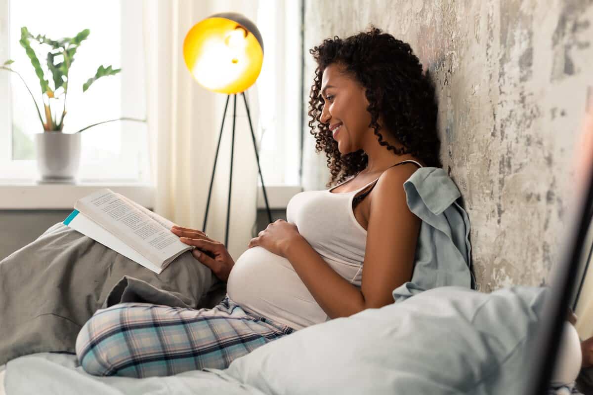 Pregnant women reading a book on her bed