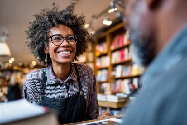 A woman smiling at someone in a bookshop.