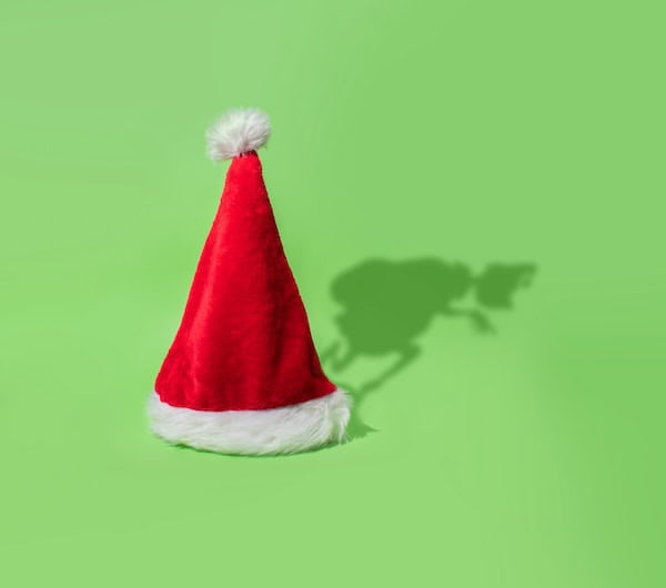A Santa hat with a shadow shaped like the Grinch.